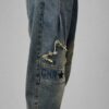spodnie jeansowe STAR Denim z aplikacjami luźne spodnie jeansowe z gumką w pasie spodnie denim z gwiazdkami i przetarciami damskie spodnie jeansowe z dekoracyjną nogawką spodnie jeansowe z dekatyzowanym wykończeniem modne spodnie denim z nadrukiem na nogawce spodnie jeansowe o swobodnym fasonie spodnie STAR Denim Butik Madzia Fashion