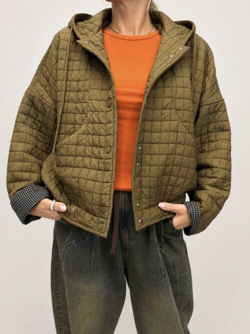 FD8EB510-F135-4FDE-A03C-6F794673DEA6 Kurtka pikowana oliwka na napy to świetna propozycja na sezon przejściowy — wygodna, stylowa i bardzo praktyczna. Ma luźniejszy, lekko oversize’owy krój, dzięki czemu pięknie układa się na sylwetce i bez problemu zmieści pod spodem sweter, bluzę albo grubszy longsleeve. Model posiada pikowanie w kratkę, kaptur z troczkami oraz zapięcie na napy. Dużym atutem są rękawy z kontrastowym podszyciem duo — można je podwinąć i uzyskać jeszcze ciekawszy efekt w stylizacji. Całość wygląda modowo, ale nadal bardzo codziennie i wygodnie. Oliwkowy kolor pięknie łączy się z jeansami, beżem, czekoladą, śmietaną i jesiennymi odcieniami. To kurtka, którą założysz zarówno do luźnych spodni, jak i do bardziej kobiecej stylizacji.